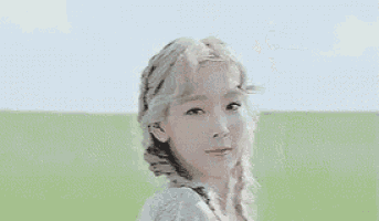 a woman with blonde hair is smiling in a field of grass .