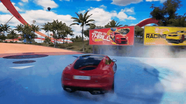 a red car is driving on a track with a hot wheels racing sign in the background