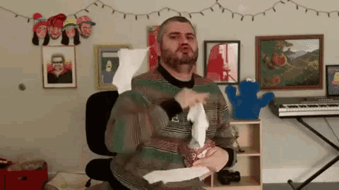 a man with a beard is blowing his nose while holding a box of kleenex