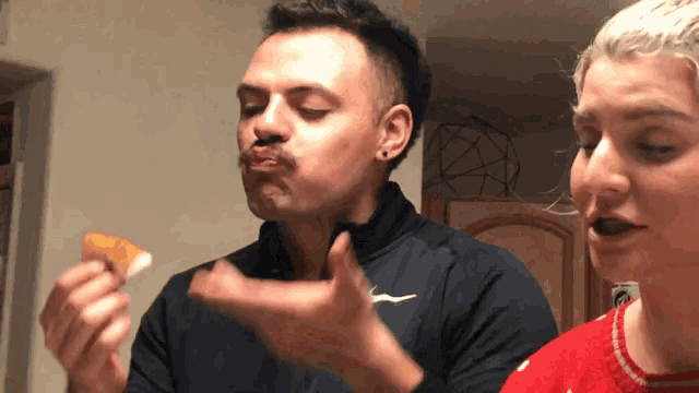 a man wearing a black nike shirt is eating a piece of pizza