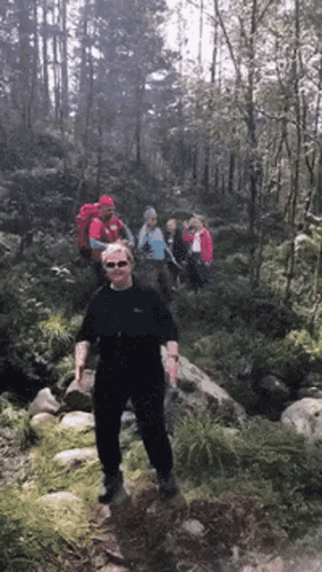 a group of people hiking in the woods with one wearing a red hat