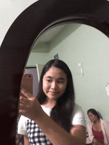 a girl taking a selfie in a mirror with her phone