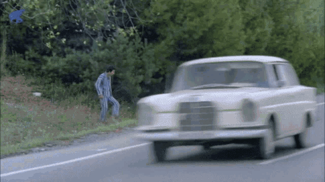 a man standing on the side of a road next to a car