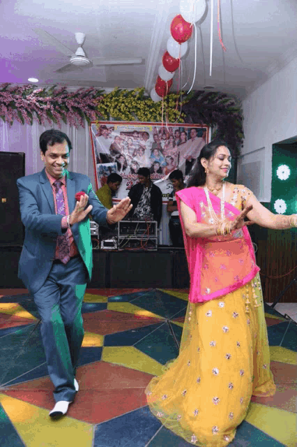 a man in a suit and a woman in a yellow dress are dancing on a colorful floor