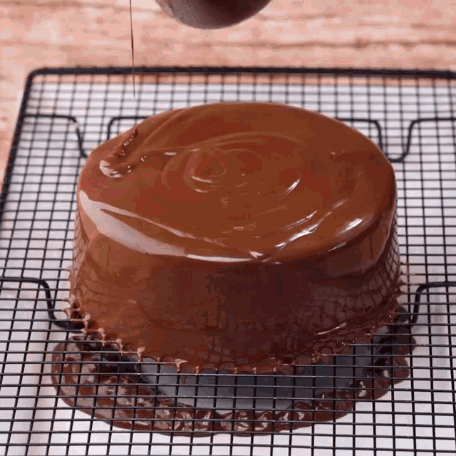 a chocolate cake is sitting on a cooling rack with chocolate being poured on it