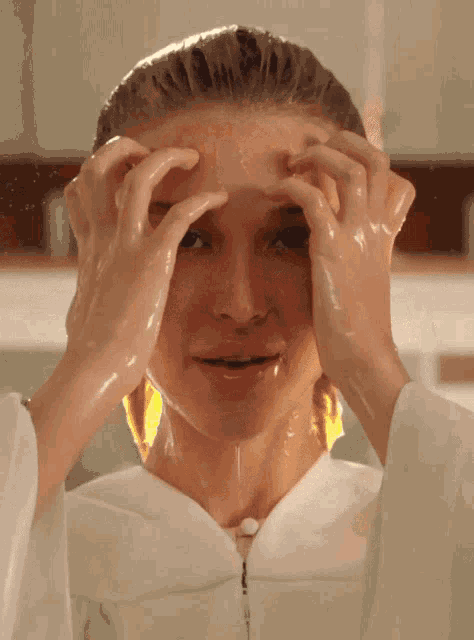 a woman with her hands on her face is covered in a thick liquid