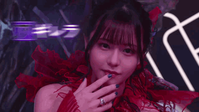 a woman in a red dress with a ring on her finger looks at the camera