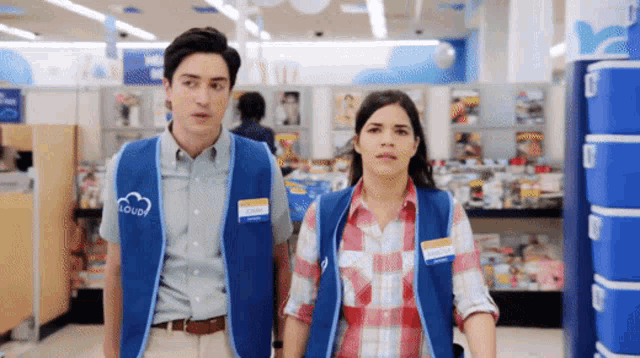 a man and a woman wearing superstore vests are standing in a store