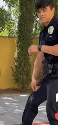 a police officer is standing on a sidewalk in front of a yellow wall .