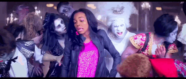 a woman in a pink dress stands in front of a group of zombies