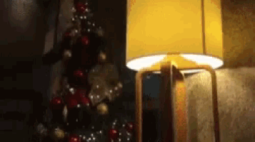 a lamp is lit up in front of a decorated christmas tree