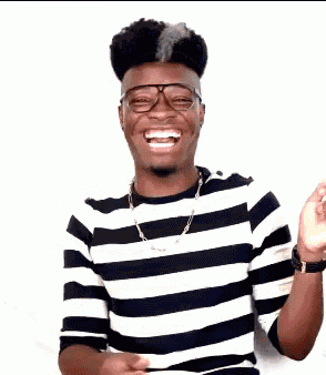 a young man wearing glasses and a striped shirt is smiling and giving a thumbs up .