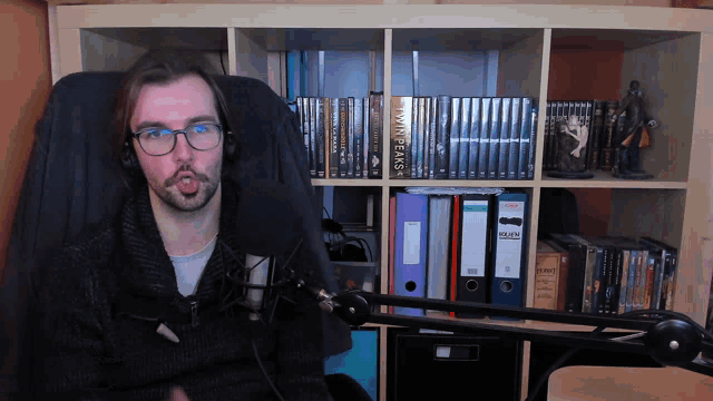 a man wearing headphones is sitting in front of a bookshelf with a book called twin peaks on it