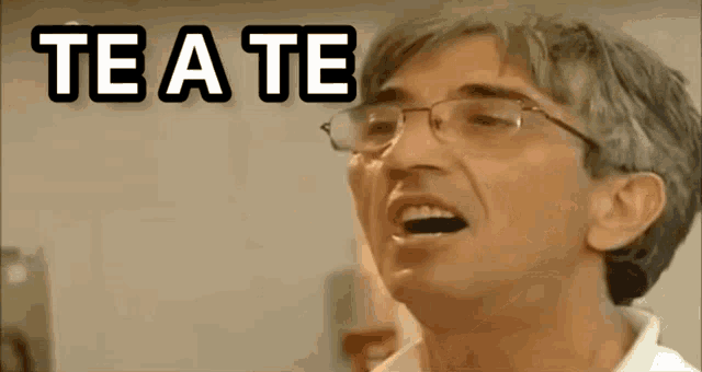 a man with glasses covering his mouth with his hand and the word te a te above him