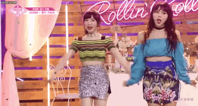 two young women are standing next to each other on a stage holding hands .