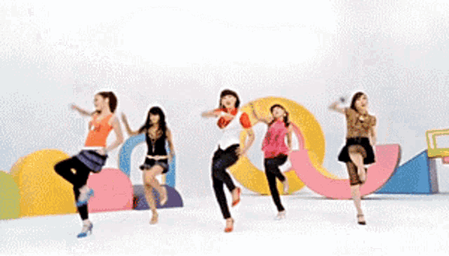a group of women are dancing in front of a white wall