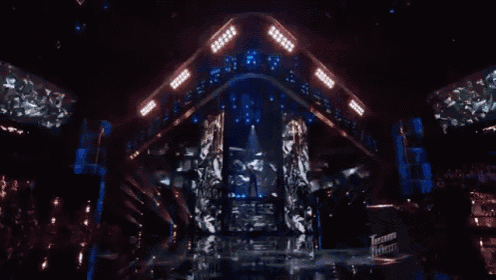 a woman singing into a microphone on a stage with a screen behind her that says teen talent