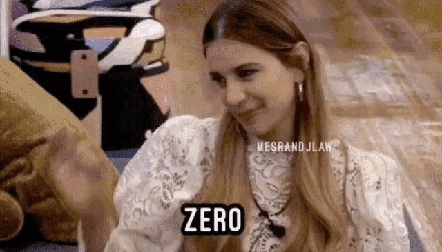 a woman in a white lace shirt is sitting on the floor and says zero .