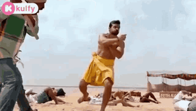 a man without a shirt is dancing on a beach .
