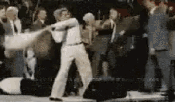 a man in a white shirt is swinging a bat in a crowd of people