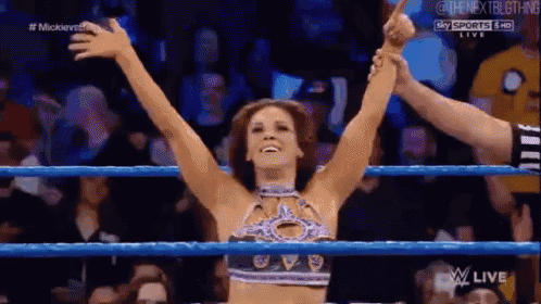 a woman is standing in a wrestling ring with her arms outstretched .