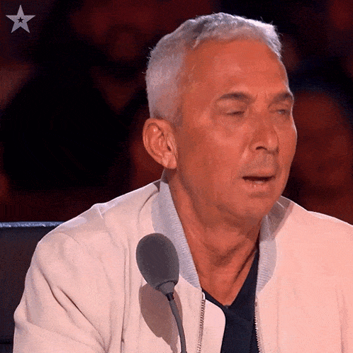 a man in a white jacket stands in front of a microphone with a star in the background