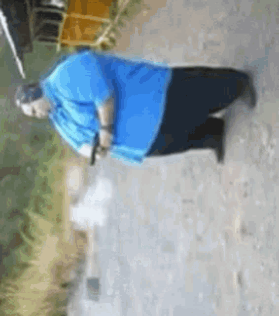 a man wearing a blue shirt and black pants is walking down a dirt road