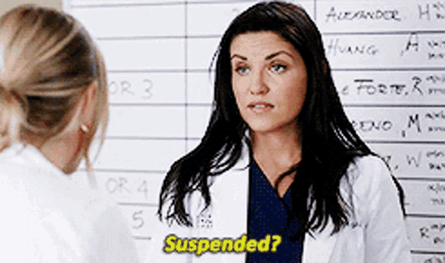 a woman in a lab coat says suspended in front of a board