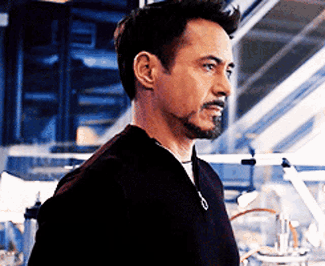 a man with a beard is standing in a room and looking to the side