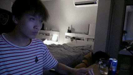 a man in a red and white striped shirt is sitting in front of a bed