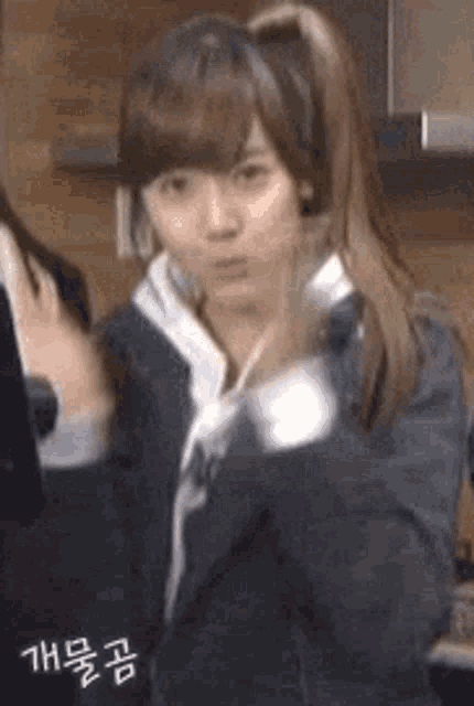 a young girl with a ponytail is standing in front of a microphone and making a funny face .