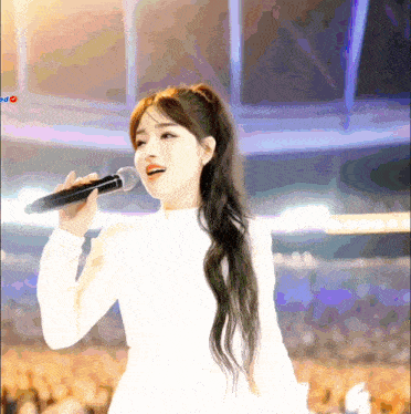 a woman singing into a microphone in front of a crowd with the word red visible