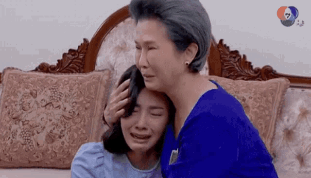 a woman is comforting another woman who is crying while sitting on a bed .