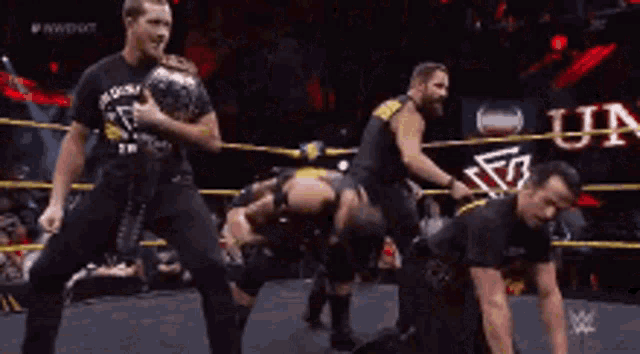 a group of wrestlers are standing in a ring .