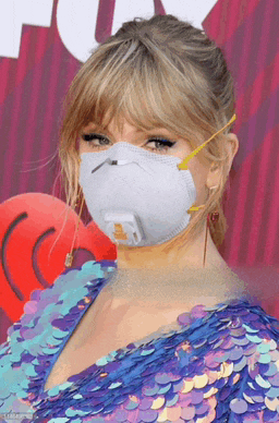 a woman in a blue sequined dress is wearing a white face mask