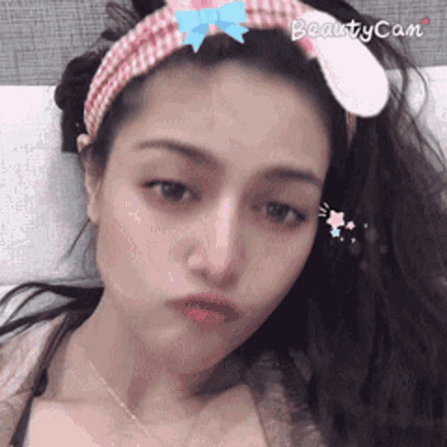 a woman wearing a headband with bunny ears is taking a picture with beauty cam