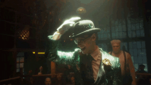 a man in a green suit and white hat is dancing