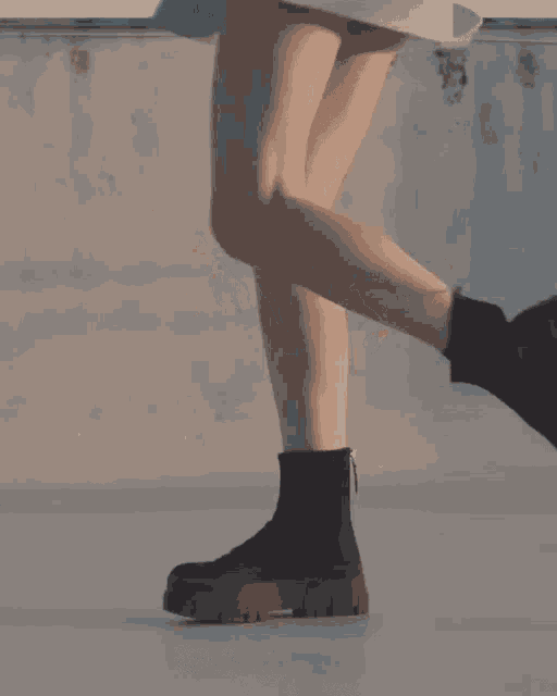 a woman wearing a skirt and black boots is walking