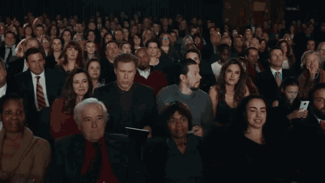 a crowd of people are taking pictures with their phones and one man is holding a tablet