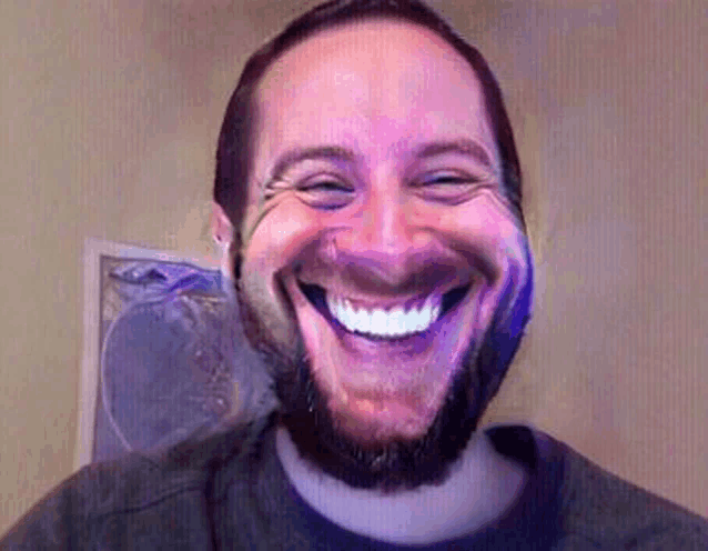 a man with a beard is smiling while wearing a purple shirt