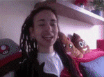 a girl with dreadlocks is smiling in front of a shelf with stuffed animals on it