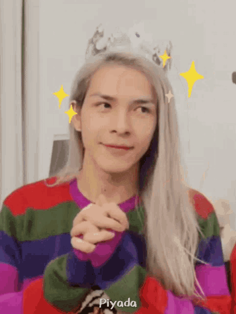 a man with long blonde hair wearing a striped sweater and a crown with the name piyada below him