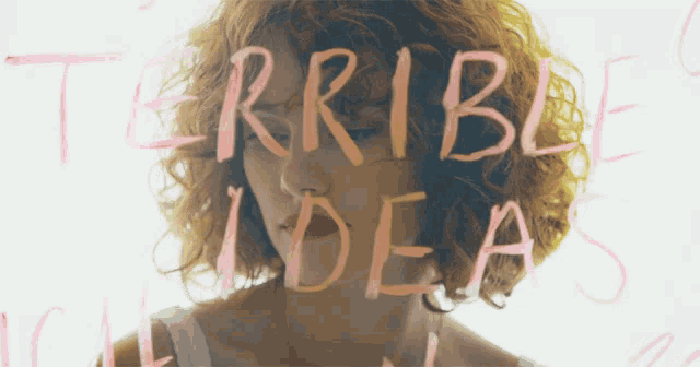 a woman with curly hair is behind the words terrible ideas written on a wall