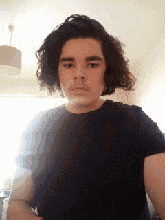 a young man with long curly hair is wearing a black t-shirt