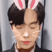 a young man wearing bunny ears on his head and a cat nose .