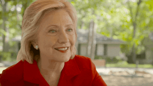 a woman in a red shirt and earrings smiles