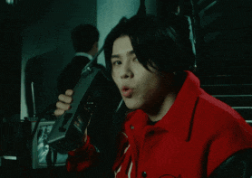 a man in a red jacket is singing into a microphone