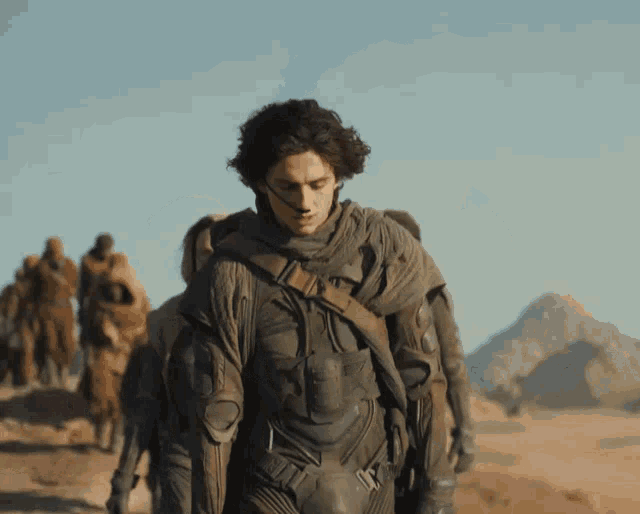 a man in a military uniform is walking through a desert
