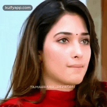 a close up of a woman 's face with a red turtleneck and earrings .