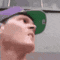 a man wearing a green hat and a purple hat is looking up at something .